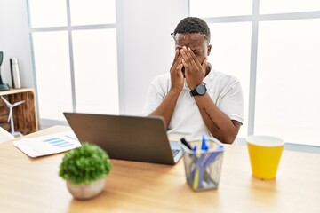 Young african man working at the office using computer laptop rubbing eyes for fatigue and headache, sleepy and tired expression. vision problem