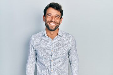 Handsome man with beard wearing casual elegant shirt looking positive and happy standing and smiling with a confident smile showing teeth