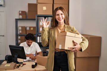 Young two people working at small business ecommerce doing ok sign with fingers, smiling friendly gesturing excellent symbol