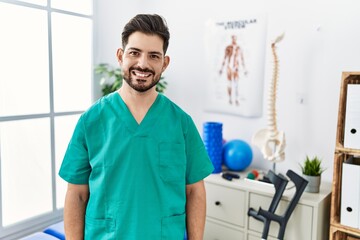 Young man with beard working at pain recovery clinic with a happy and cool smile on face. lucky person.