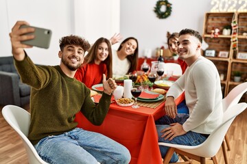 Group of young people having christmas dinner make selfie by the smartphone at home.