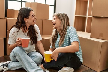 Young couple smiling happy drinking cup of coffee at new home.