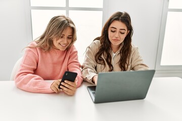 Young couple smiling happy working using laptop and smartphone at home.