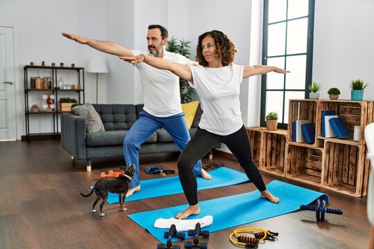 Middle age hispanic couple smiling happy training at home.