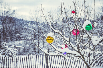 Bunte Christbaum im Winter für draussen, bunte Christbaumkugeln, Weihnachtspostkarte, Hintergrund Weihnachten, verschneiter Baum mit Christbaumkugeln