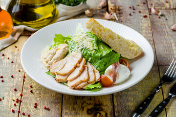 Salad caesar with chicken on white plate on wooden table