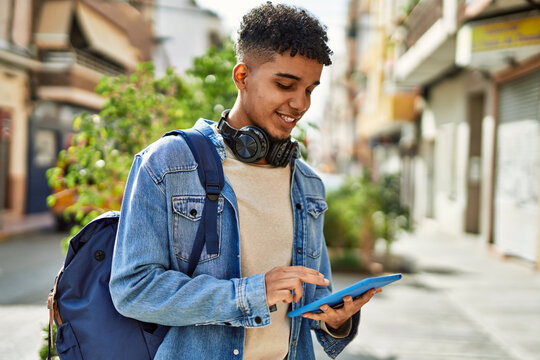 Hispanic young man using touchpad device at the street