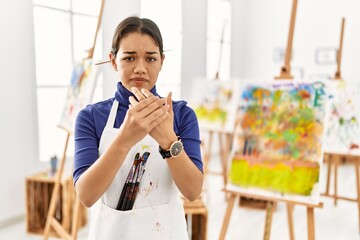 Young brunette woman at art studio suffering pain on hands and fingers, arthritis inflammation