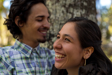 Young latin couple (28) smile happily. Selective focus on the woman's face. Valentine's Day concept, couples and friendships.