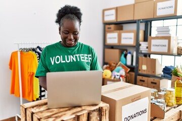 Young african american woman wearing volunteer uniform using laptop working at charity center