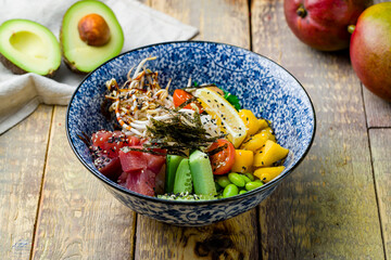 Ahi poke with tuna, cucumbers, mango, edamame, chukka, lemon and boiled rice side view on wooden table
