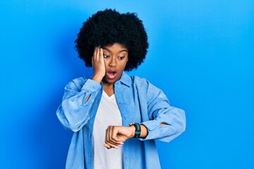 Young african american woman wearing casual clothes looking at the watch time worried, afraid of...
