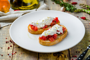 bruschetta with tomatoes and cheese strachatella on wooden table