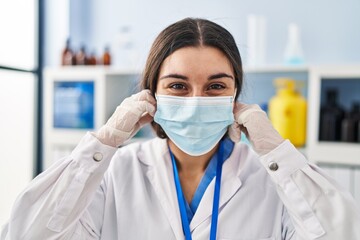 Young hispanic woman wearing scientist uniform and medical mask at laboratory