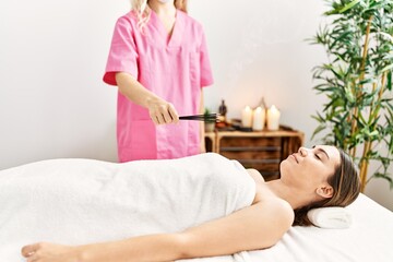 Obraz na płótnie Canvas Young hispanic woman having incense aromatherapy at beauty center.