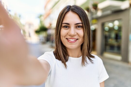 Young beautiful woman smiling happy outdoors on a sunny day of summer taking a selfie picture