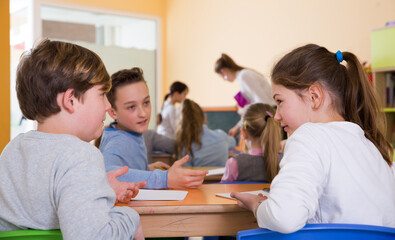Obraz na płótnie Canvas Portrait of schoolchildren sitting in classroom and chatting during lesson