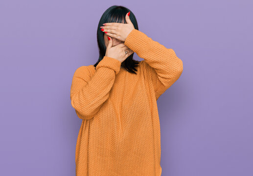 Young hispanic woman wearing casual clothes covering eyes and mouth with hands, surprised and shocked. hiding emotion