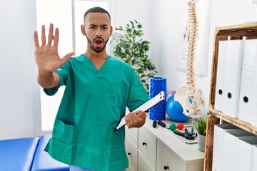 African american physiotherapist man working at pain recovery clinic doing stop gesture with hands palms, angry and frustration expression