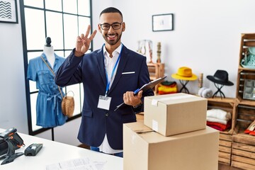 African american man working as manager at retail boutique smiling looking to the camera showing fingers doing victory sign. number two.