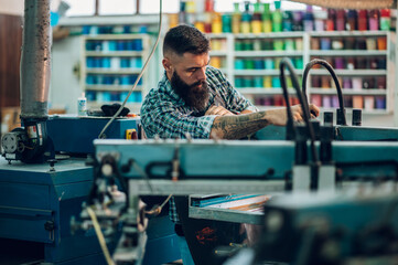 Male worker using printing machine in a workshop