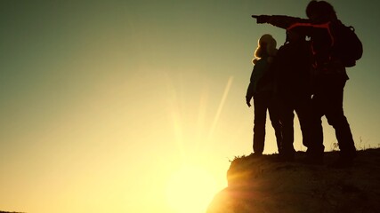 Silhouettes of Tourists climbed to the top of the mountain rejoice in the victory over the winter sunset. Teamwork of people. The travelers met at the peak of their success. Teamwork, victory, success