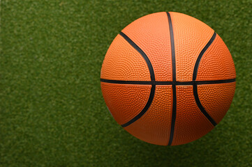 Orange basketball ball on a green sports field. Close-up. Minimalism. There is a place to insert. Sports, outdoor activities, healthy lifestyle.