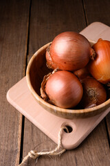 Red and white onions on a wooden cutting board on a rustic wooden table in the kitchen, top view. High quality photo