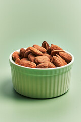  Bowl of delicious almonds over green background