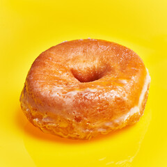  SIngle glazed doughnut over yellow background