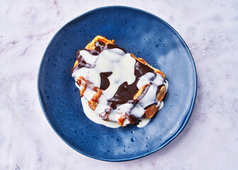  Plate of delicious waffle with chocolate and cream on marble surface