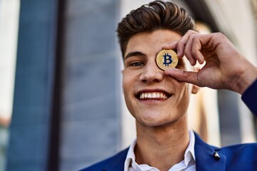 Young man wearing suit holding bitcoin over eye at street