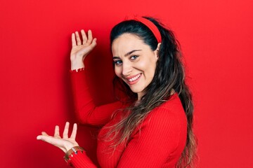 Young hispanic woman wearing casual clothes inviting to enter smiling natural with open hand