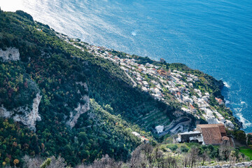 The Italian village of Praiano, seen from above, from the Path of the Gods (Sentiero degli Dei) along the scenic Amalfi Coast of Italy, with the blue Tyrrhenian Sea and blue sky and clouds