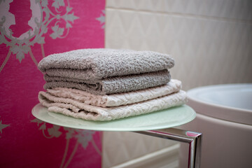 A stack of towels on a shelf dryer for things in the bathroom