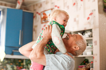 grandfather play with the child's grandchildren at home in family relationships. A young girl hugs an elderly man