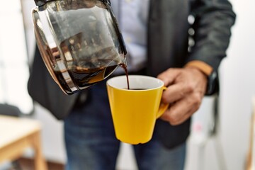 Middle age caucasian man pouring coffee on cup at office