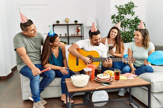 Group of young hispanic friends having birthday party playing spanish guitar at home.