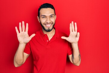 Hispanic man with beard wearing casual red t shirt showing and pointing up with fingers number nine...