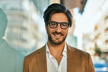 Young hispanic businessman smiling happy standing at the city.
