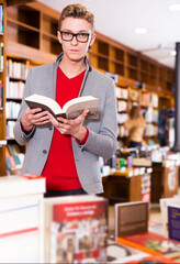 Intelligent serious man searching for information in books in bookstore