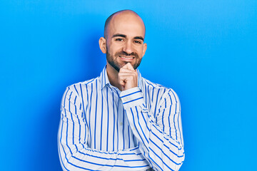Young bald man wearing elegant clothes smiling looking confident at the camera with crossed arms and hand on chin. thinking positive.