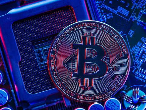 Macro photography. In the foreground is bitcoin cryptocurrency on the desktop of a personal computer processor. Blue neon lighting. New computer and financial technologies, nanotechnologies. - Powered by Adobe