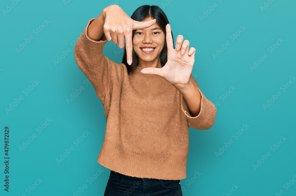 Wall mural beautiful young asian woman wearing casual winter sweater smiling making frame with hands and finger