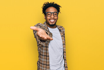 Young african american man with beard wearing casual clothes and glasses smiling cheerful offering palm hand giving assistance and acceptance. - Powered by Adobe