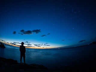 夜明け前の星空と人物