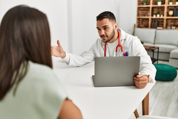 Fototapeta premium Doctor explain treatment to latin woman using laptop at clinic