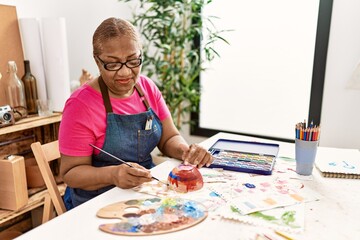 Senior african american woman smiling confident painting clay ceramic at art studio