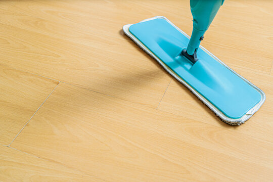 Top view of a mop head with its microfiber cloth cleaning a light parquet floor. Concept of domestic hygiene, cleaning, housework.