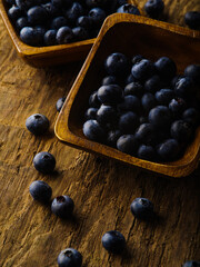 Delicious fresh blueberries in a bowl and near it on the table. High angle view. Close-up. Cooking, agriculture, forestry. Cooking, ingredients, juices, fresh juices. Culinary blog, advertisement.